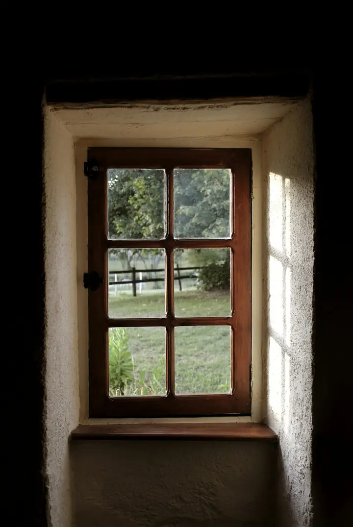 Small cottage window set deep in a thick stone wall